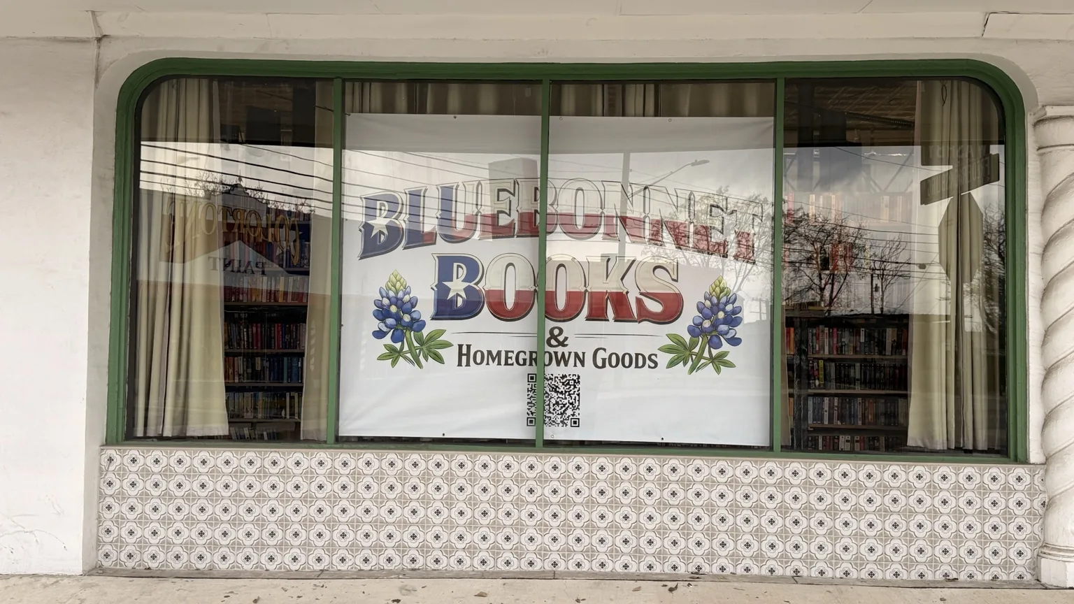 Storefront sign displayed in the window of Bluebonnet Books & Homegrown Goods.